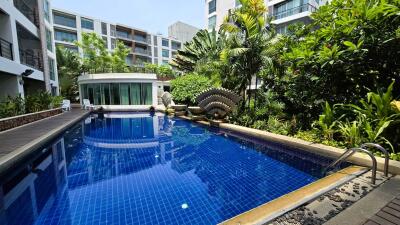 Blue swimming pool in a luxurious apartment complex with lush garden and modern amenities