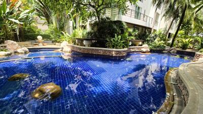 Luxurious outdoor swimming pool surrounded by lush tropical plants and a modern residential building