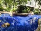 Luxurious outdoor swimming pool surrounded by lush tropical plants and a modern residential building