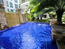 Luxurious outdoor swimming pool with water features and lush greenery in a modern residential apartment complex