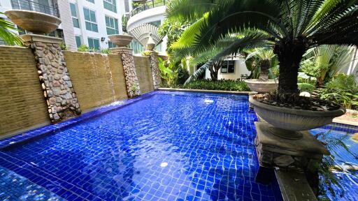 Luxurious outdoor swimming pool with water features and lush greenery in a modern residential apartment complex
