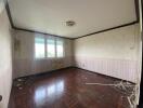 Spacious bedroom in need of renovation with wooden flooring and large windows