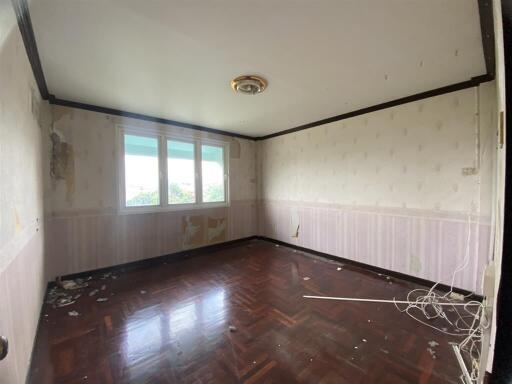 Spacious bedroom in need of renovation with wooden flooring and large windows