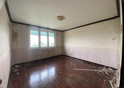 Spacious bedroom in need of renovation with wooden flooring and large windows