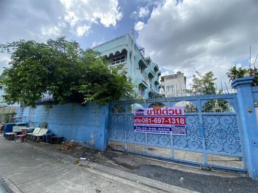 Blue gated entrance to a residential building with lush greenery