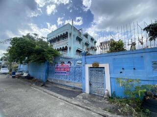 Blue painted residential building exterior with decorative metal gate and balcony