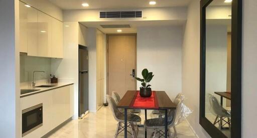 Modern kitchen with dining area featuring glossy white cabinets and stainless steel appliances