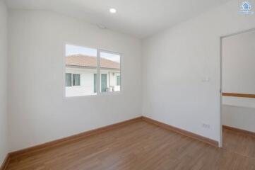 Spacious and well-lit empty bedroom with wooden flooring