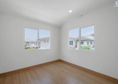 Bright and empty bedroom with wooden flooring and dual windows