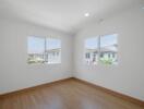 Bright and empty bedroom with wooden flooring and dual windows