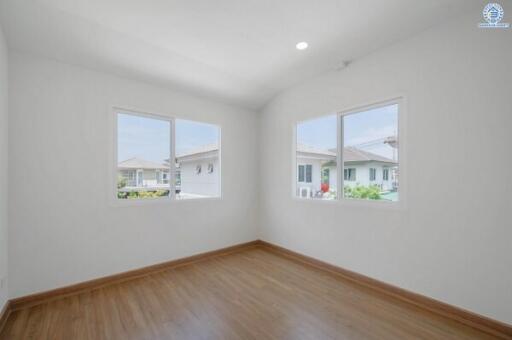 Bright and empty bedroom with wooden flooring and dual windows