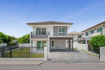 Modern two-story house with balcony and landscaped front yard