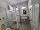 Spacious modern bathroom with glass shower enclosure and white fixtures