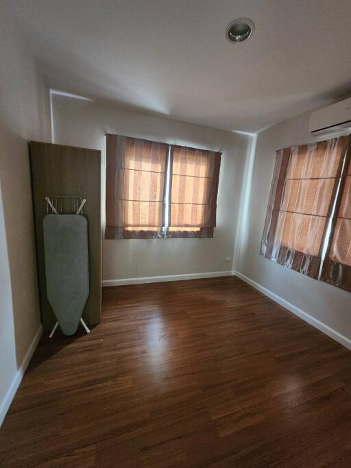 Bedroom interior with wooden flooring and window with brown curtains