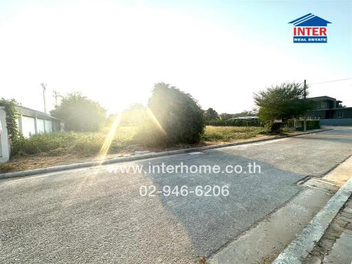 Sunlit street view of a residential area with visible property signage