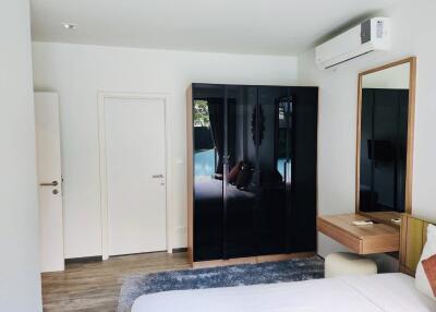 Spacious modern bedroom with reflective wardrobe and wooden accents