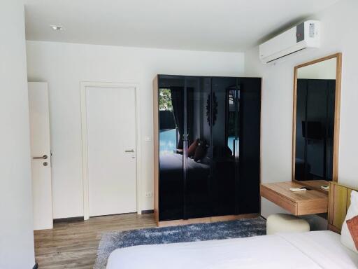 Spacious modern bedroom with reflective wardrobe and wooden accents