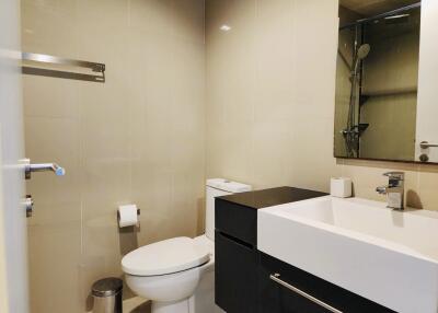 Modern bathroom with beige tiles, white sink and toilet