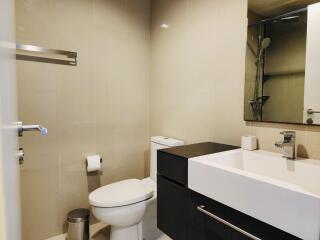 Modern bathroom with beige tiles, white sink and toilet