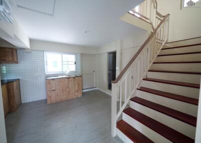 A kitchen area with wooden cabinets and a staircase.