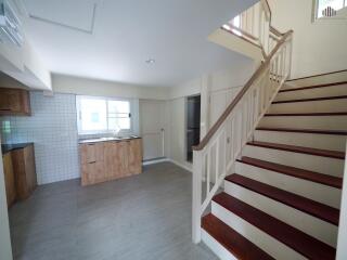 A kitchen area with wooden cabinets and a staircase.