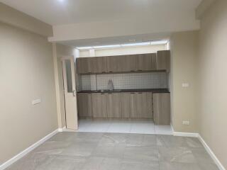 Modern kitchen with light wood cabinetry and tile flooring