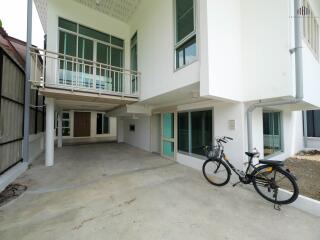 Exterior view of a modern white building with a covered area and a bicycle