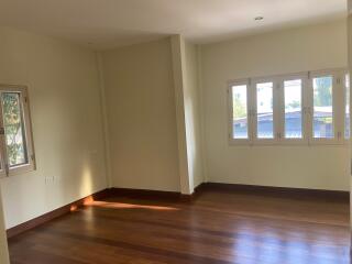 Spacious living room with hardwood flooring and ample natural light from multiple windows