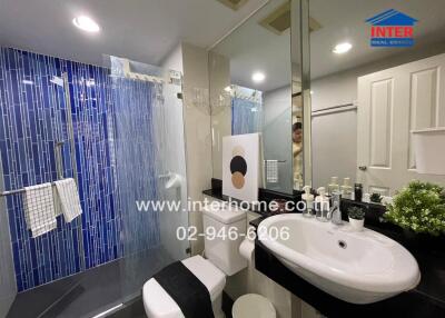Modern bathroom interior with blue tile shower area and white fixtures