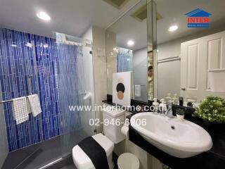 Modern bathroom interior with blue tile shower area and white fixtures