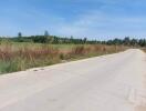 Rural road adjacent to undeveloped land with clear skies