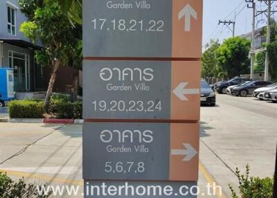 Directional signboard for Garden Villa real estate with visible contact information and website