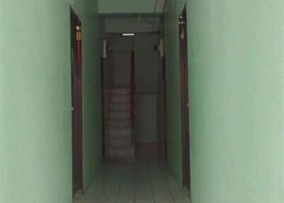 Long narrow corridor in a residential building with tiled floors and multiple doors