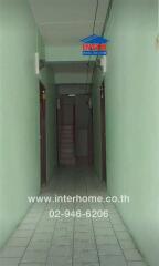 Long narrow corridor in a residential building with tiled floors and multiple doors