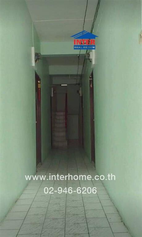 Long narrow corridor in a residential building with tiled floors and multiple doors