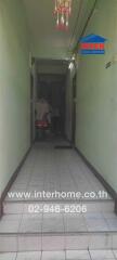 Narrow residential building hallway with pale green walls and tiled floor