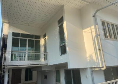 Modern white building facade with balcony in sunlight