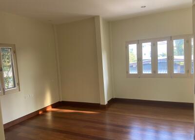 Sunlit empty living room with wooden floors