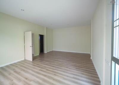 Spacious empty living room with wood flooring and an open door