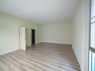 Spacious empty living room with wood flooring and an open door