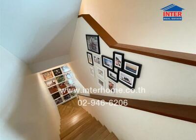 Interior view of a staircase in a home with wooden steps and framed photographs on the wall