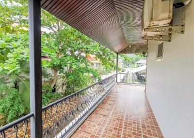 Spacious balcony with red tile flooring and lush greenery view