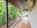 Spacious balcony with red tile flooring and lush greenery view