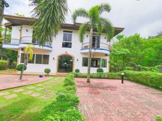 Spacious two-story house with large front yard and lush greenery