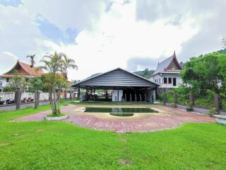 Luxurious residential property with spacious lawn and outdoor seating area adjacent to a covered parking