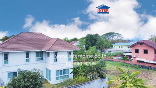 Exterior view of a spacious two-story house with a red roof and surrounding greenery