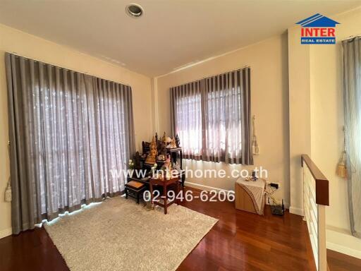 Spacious and well-lit living room with large windows and hardwood floors