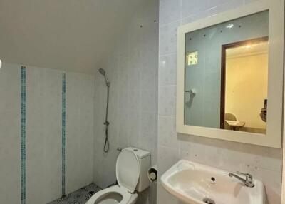 Compact bathroom with modern tiled flooring, white sanitary fixtures, and well-lit mirror