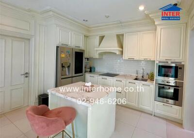 Elegant white themed kitchen with modern appliances and a stylish breakfast bar