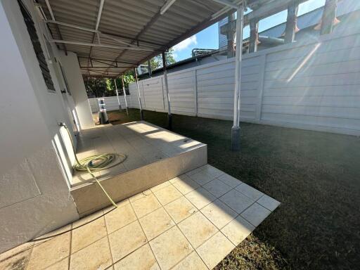 Spacious backyard with tiled patio and garden hose